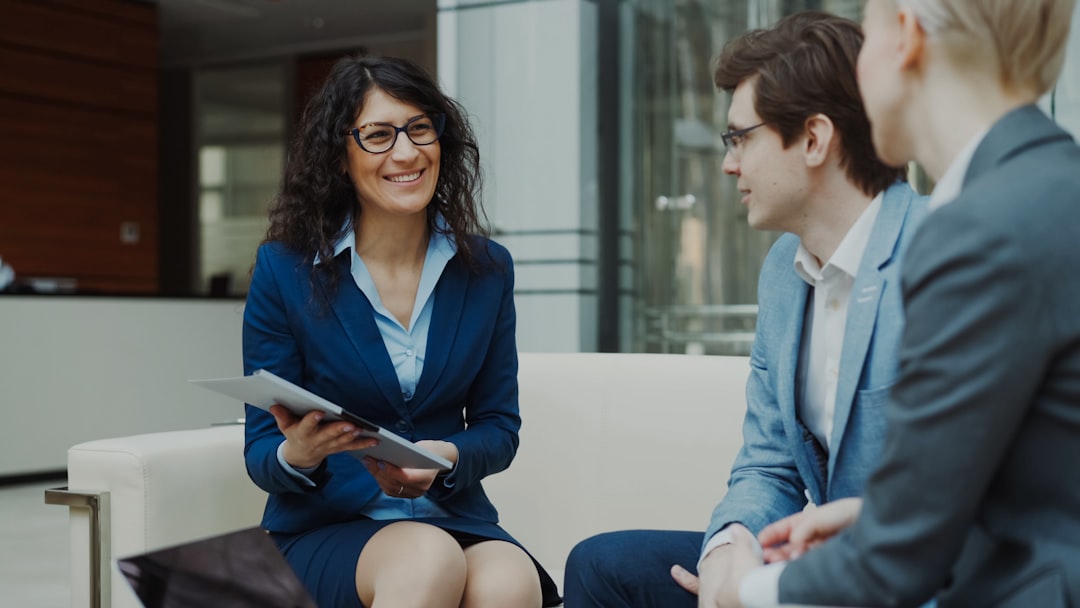 creative Businesswoman in glasses talking and duscussing future contract with business partners sitting on couch in modern office indoors